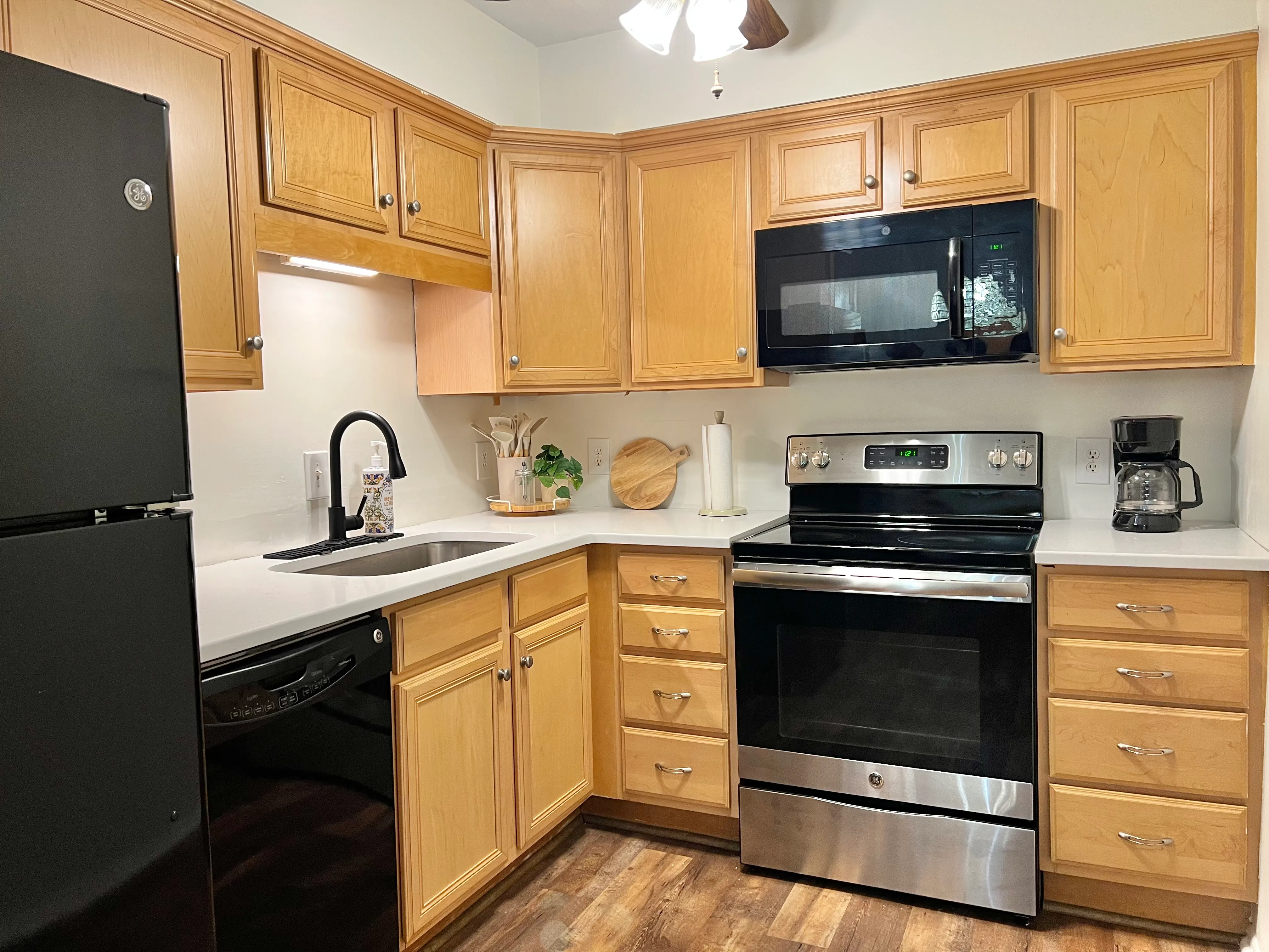 Kitchen with maple cabinets, white quartz counters, and stainless range